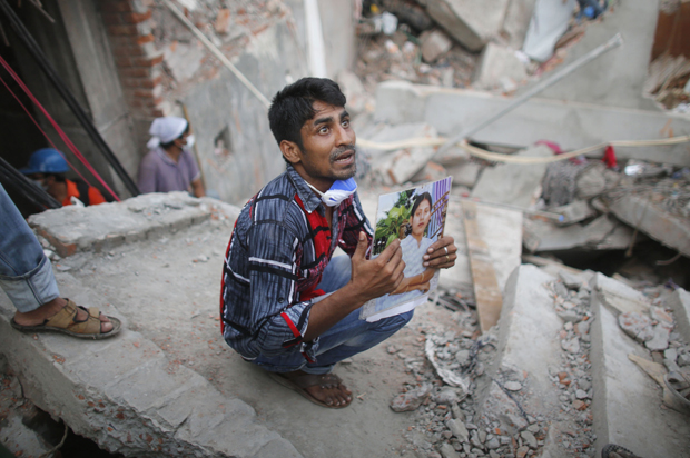 成衣女工的家人，在孟加拉熱那大廈殘骸前拿著照片尋找一線生還的可能。2013年的這場工安意外殺死了千名勞工。
