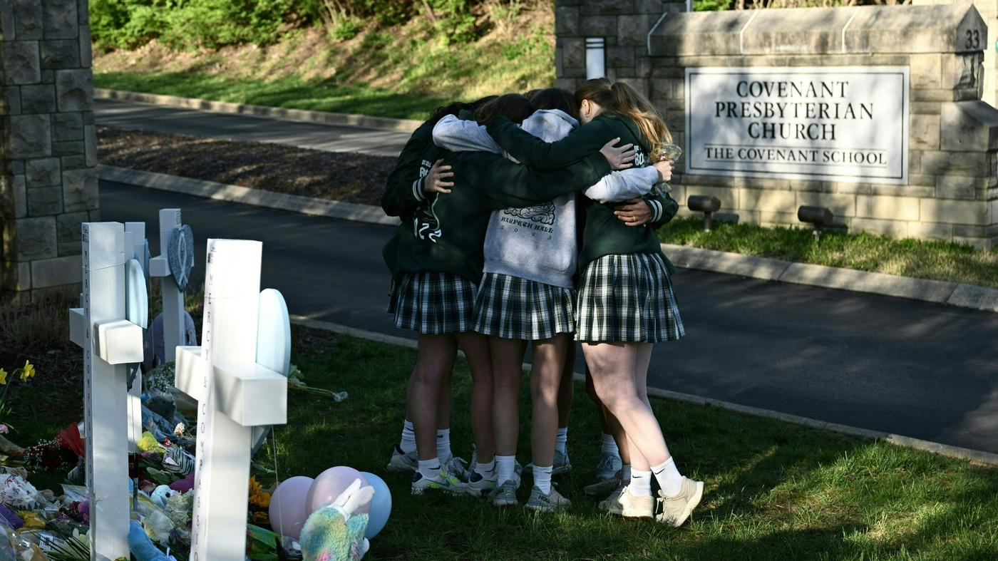 在聖約小學外的臨時紀念碑，一群學童擁抱祈禱。（圖：AFP）